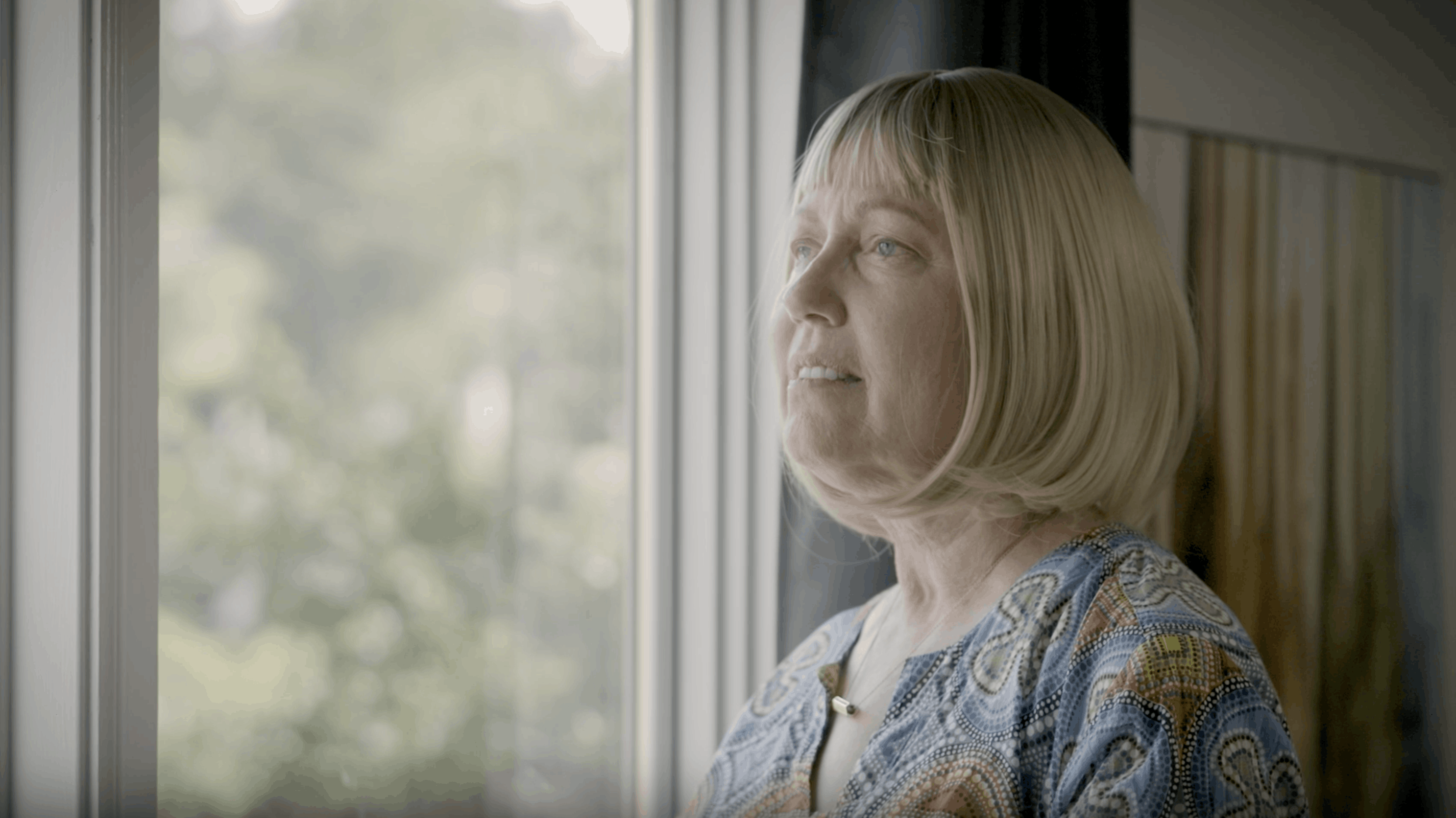 Esther looks out through a window in her home.