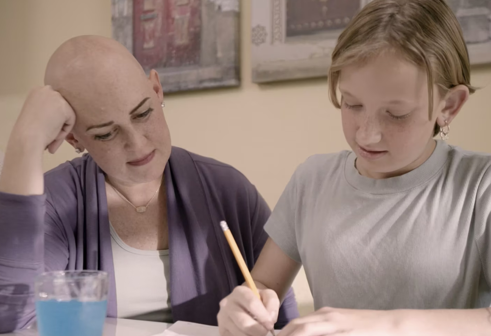Lauren sits at a table doing homework with her daughter.