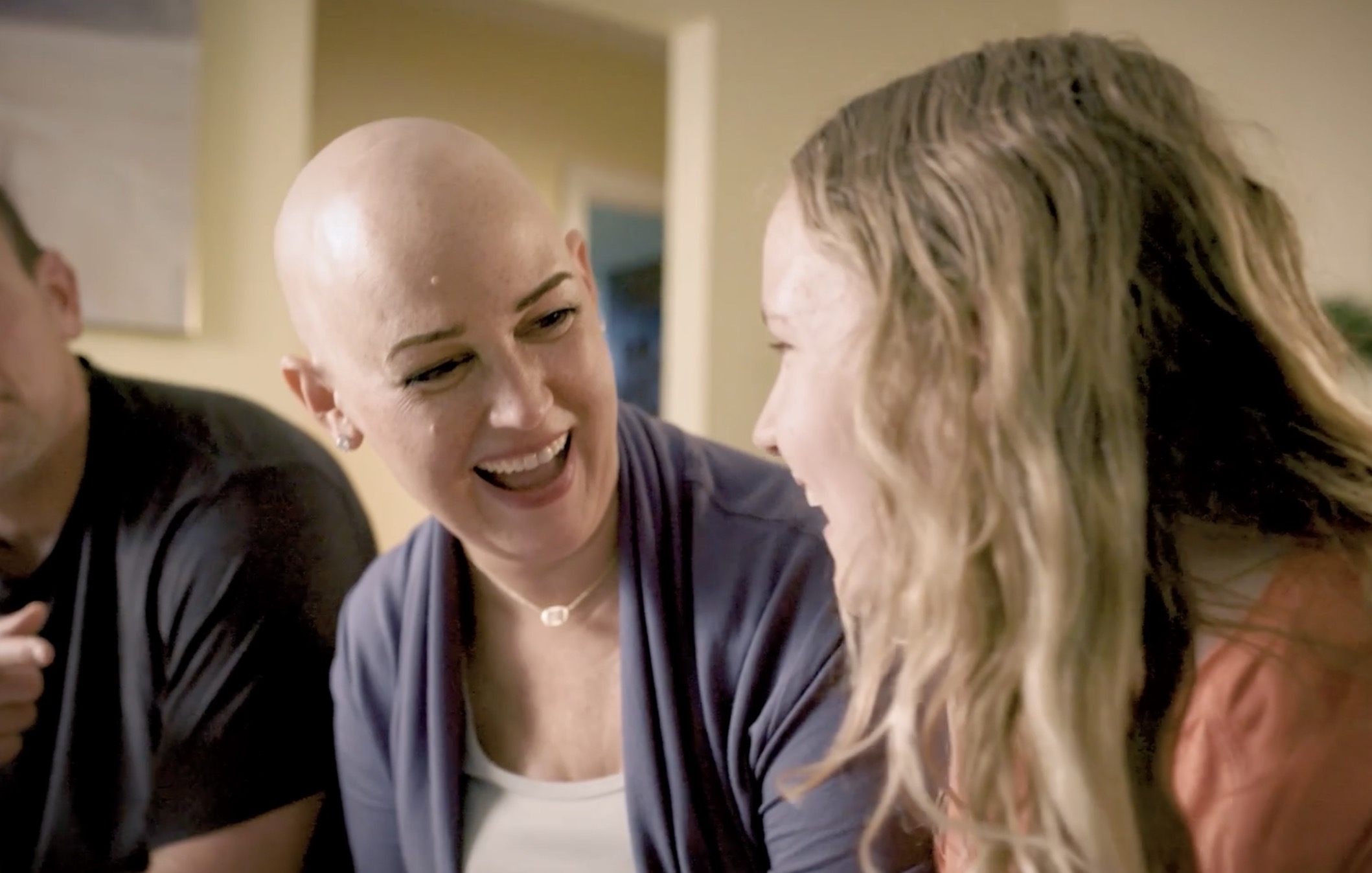 Lauren laughs with her daughter beside her at home.