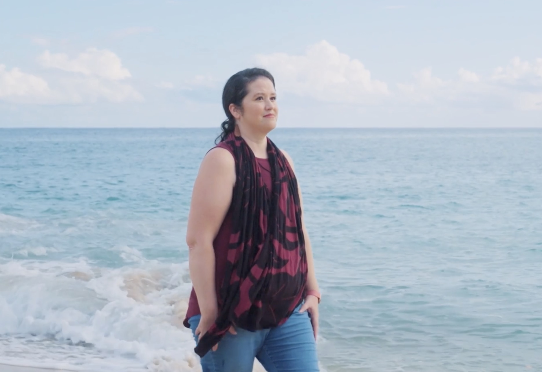 Melissa stands at the shore of a lake in a patterned scarf.