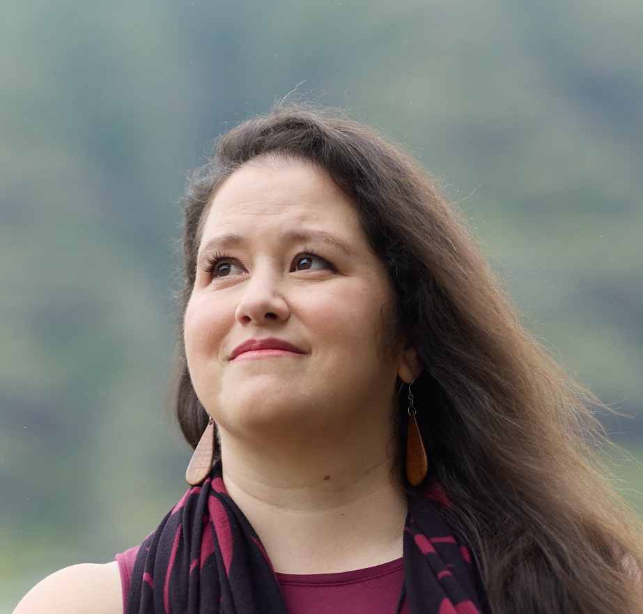 Melissa looks up and smiles, outdoors in soft light.