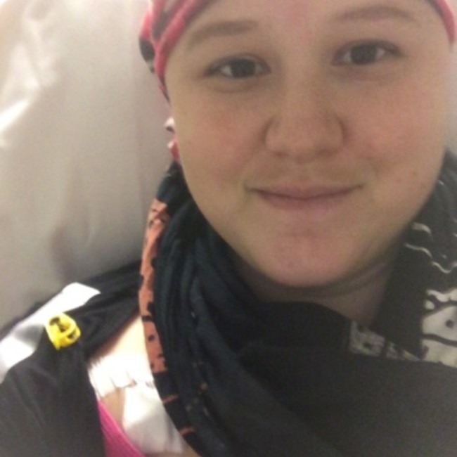 Melissa smiles at the camera in a pink and blue headwrap.